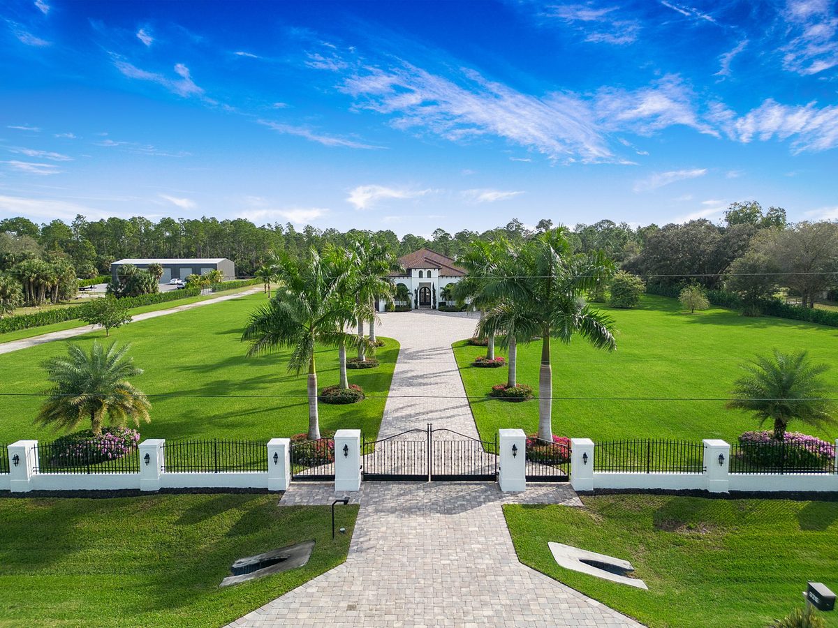 Gated luxury estate with long palm-lined paver driveway in Naples, Florida