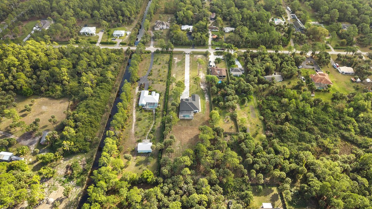 Aerial view of estate homes on wooded acreage lots along a canal in Naples, Florida