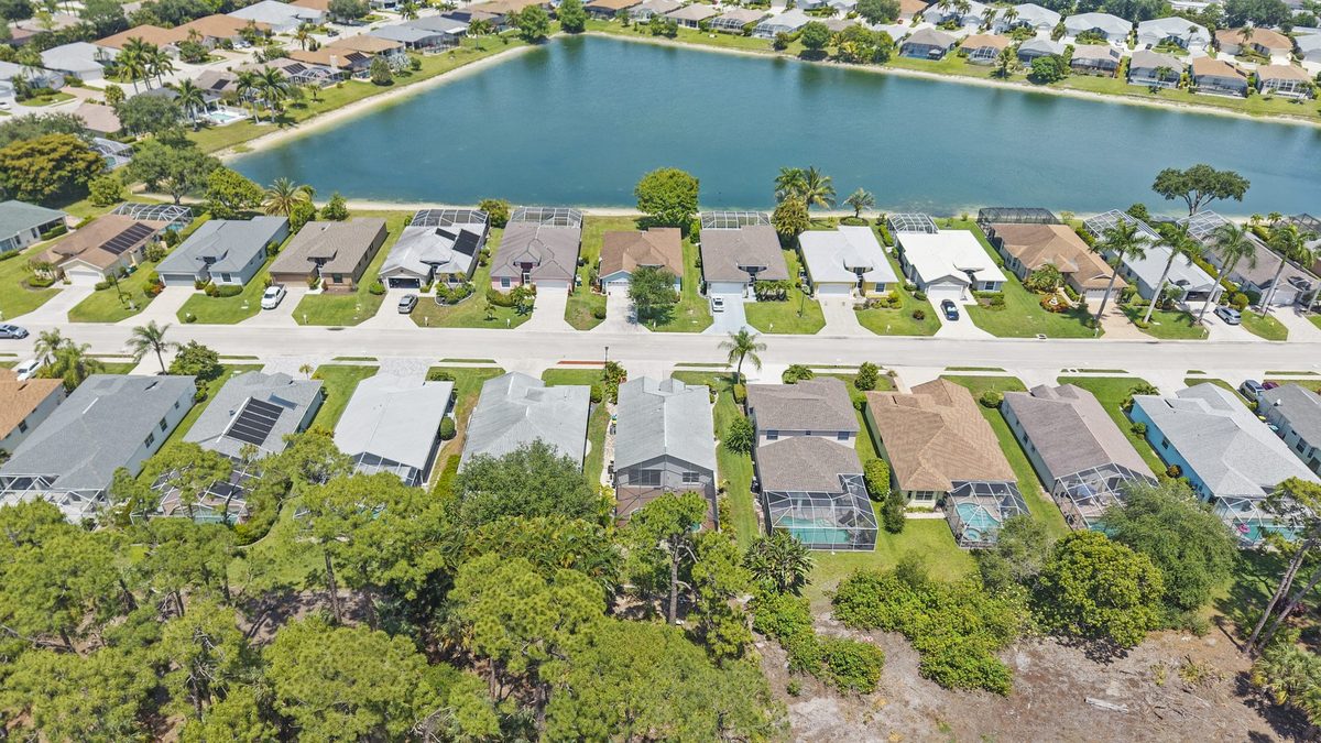 Aerial view of single-family homes along a lake in Berkshire Lakes, Naples, Florida
