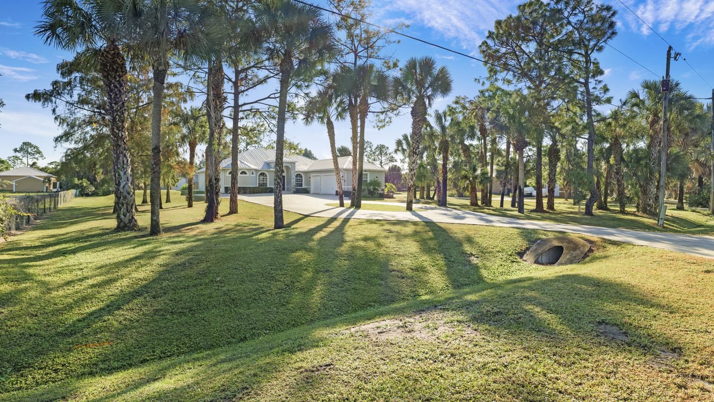Palm-lined driveway leading to a home on acreage east of Naples — what the beach premium trades for