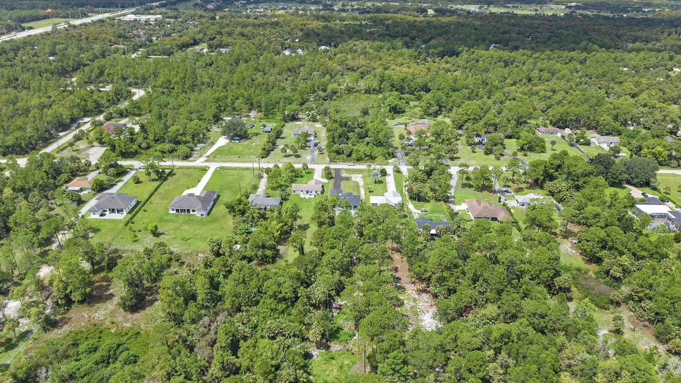 Wide aerial of a Golden Gate Estates neighborhood in Naples, Florida showing homes, cleared lots and pine forest