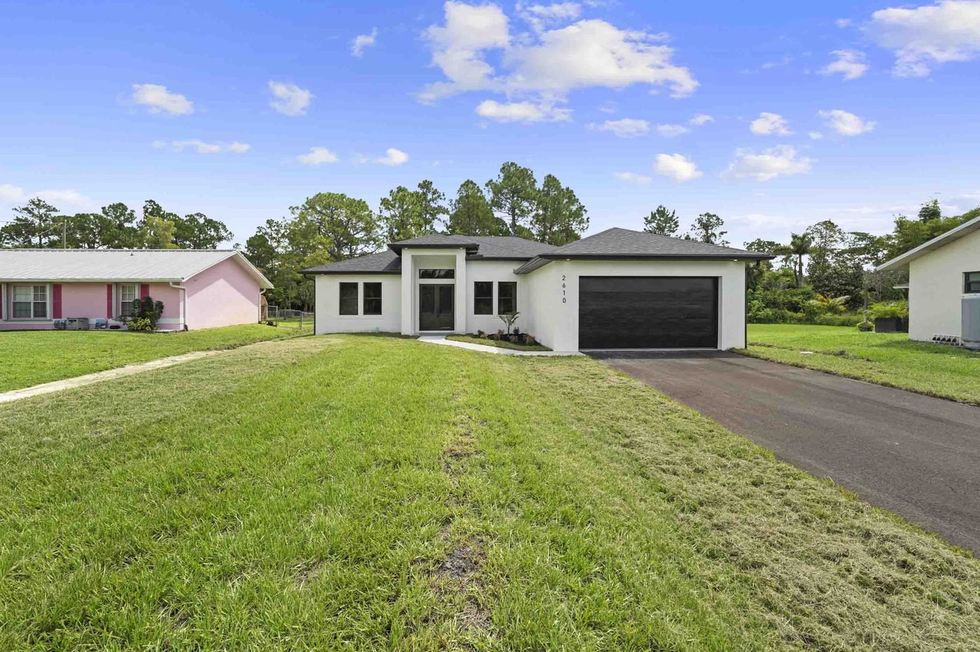 Front of a newly finished Golden Gate Estates home with a black garage door, ready to list before snowbird season in Naples, Florida