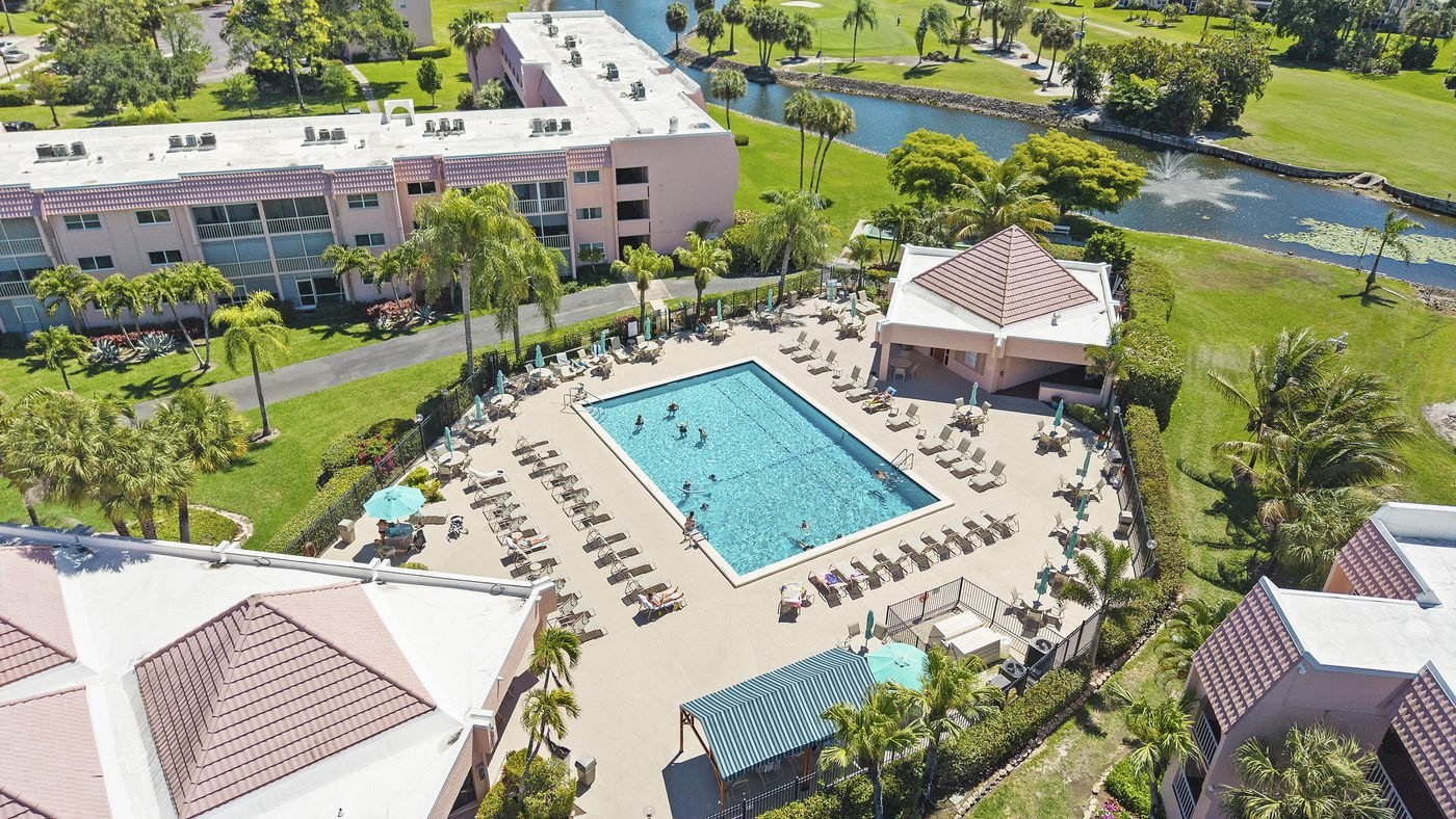 Aerial of the community pool and low-rise condo buildings at a central Naples, Florida golf community