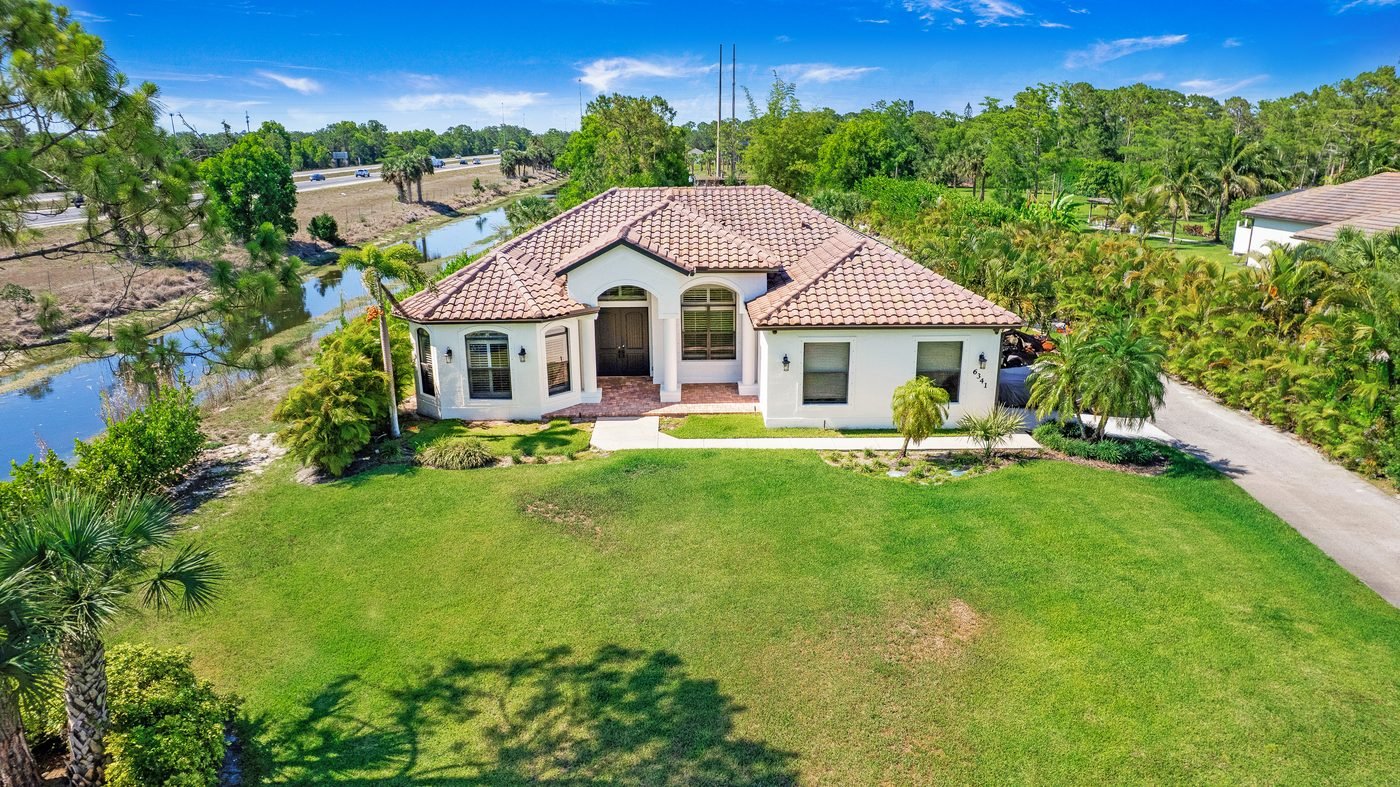 Aerial of a Golden Gate Estates home on nearly 3 acres at 6341 Green Blvd in Naples, Florida, with a wide lawn and tile roof