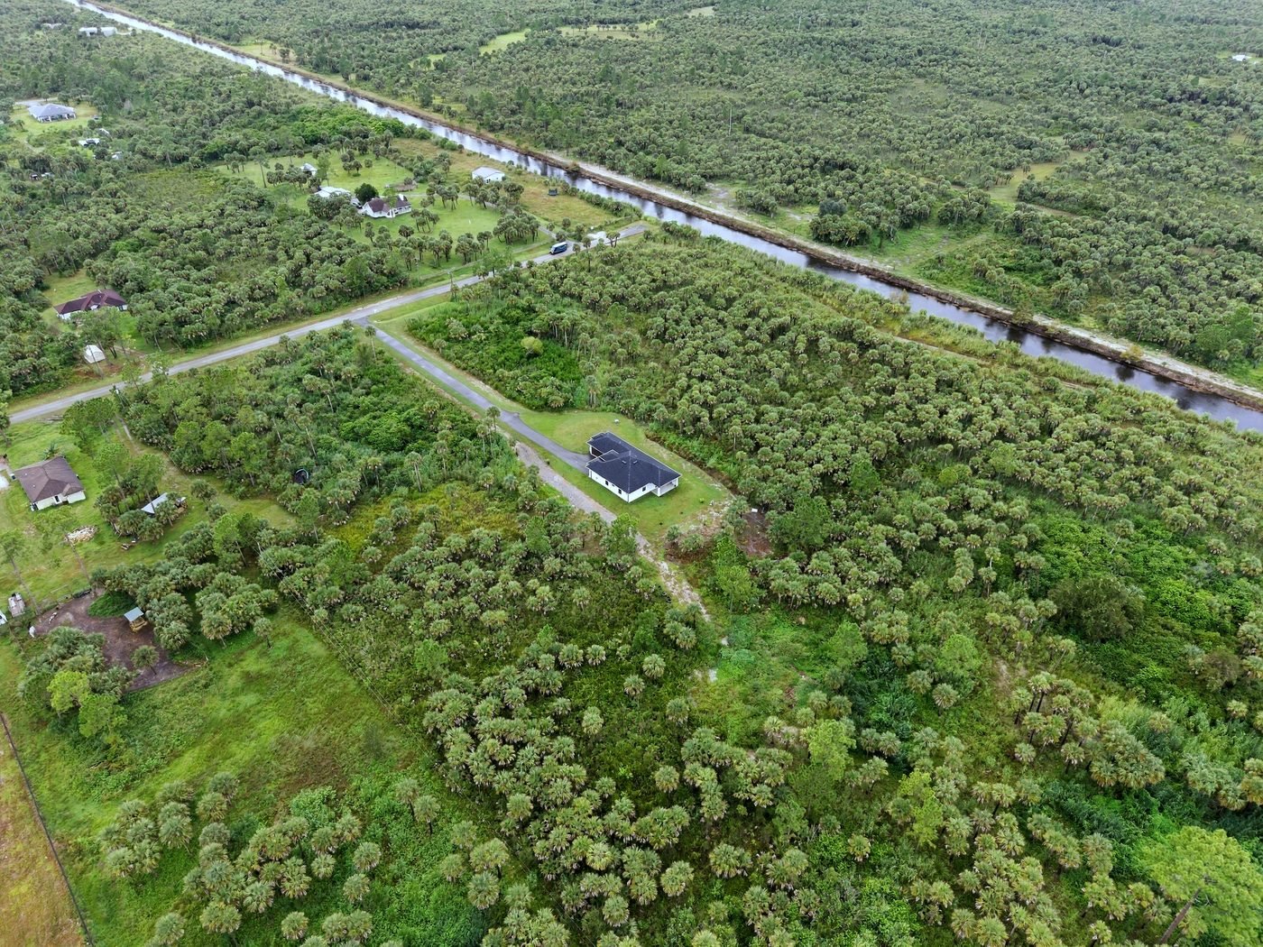 Aerial view of a new home on 2.5 wooded acres beside a canal in Golden Gate Estates, Naples, Florida