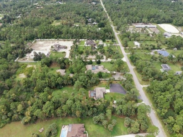 Aerial of wooded acreage lots and homes along a road in Golden Gate Estates, Naples, Florida