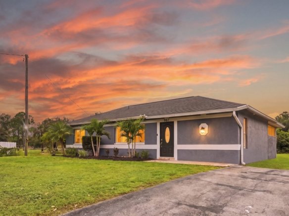 Concrete block home with a stone exterior on 2.28 acres in Golden Gate Estates, Naples, Florida, at twilight