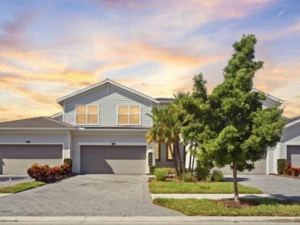 Coach home with a three-car garage at The National Golf and Country Club in Ave Maria near Naples, Florida, at twilight